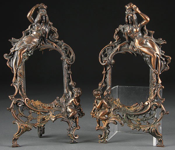 A MATCHING PAIR OF "BEATRICE" COPPERED CAST IRON : A MATCHING PAIR OF "BEATRICE" COPPERED CAST IRON ART NOUVEAU PICTURE FRAMES, of opposing form depicting a young beauty with cupid. Height 13 inches (one missing rear folding leg).