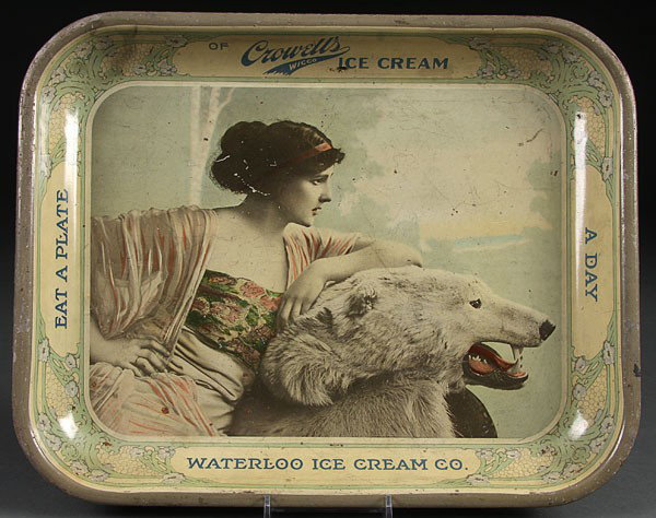 A CROWELL'S WATERLOO ICE CREAM CO. LITHOGRAPH ADV: A CROWELL'S WATERLOO ICE CREAM CO. LITHOGRAPH ADVERTISING SERVING TRAY, depicting a young beauty with polar bear rug. Length 13.25 inches.