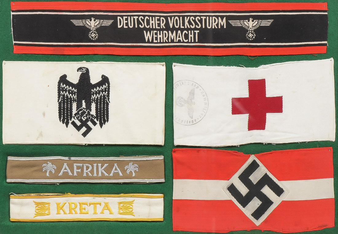 GERMAN WWII CUFF TITLES, ARMBANDS & FLAGS: GERMAN WWII CUFF TITLES, ARMBANDS & FLAGS. Comprising a framed group of six individual pieces including a good silk embroidered KRETA cuff title, a silk on wool embroidered AFRIKA cuff title, an Army 