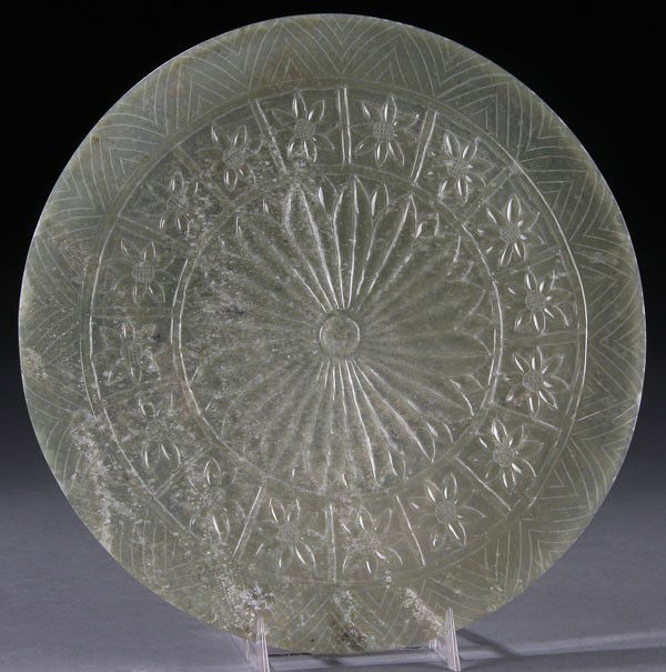A CHINESE CARVED MUGHAL STYLE WHITE JADE ROUNDEL.: A CHINESE CARVED MUGHAL STYLE WHITE JADE ROUNDEL. Of flat circular form thinly carved in translucent pale celadon toned white jade and decorated with a border of rosettes surrounding a central floral