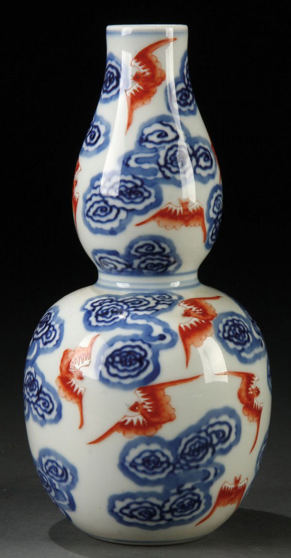 A CHINESE IRON RED AND BLUE DECORATED "BATS" VASE: A CHINESE IRON RED AND UNDERGLAZE BLUE DECORATED "EIGHTEEN BATS" PORCELAIN DOUBLE GOURD VASE, XUANTONG MARK AND OF THE PERIOD. Of double gourd form with iron red oxide bats and white enamel accents ov