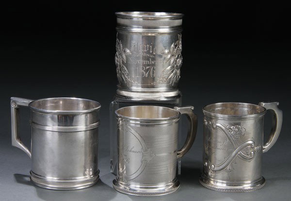 FOUR AMERICAN STERLING SILVER HANDLED MUGS: A GROUP OF FOUR AMERICAN STERLING SILVER HANDLED MUGS, 19TH CENTURY. Comprising two Wood & Hughes handled remembrance mugs, one with a repousse scrolled cartouche, the other with engine turned ground.