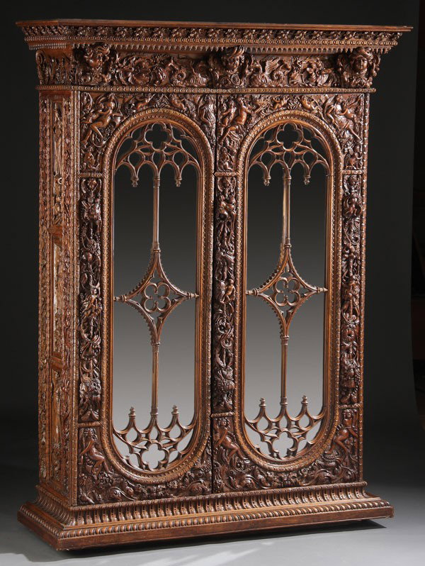 A FINE ITALIAN RENAISSANCE REVIVAL CARVED ARMOIR: AN EXTREMELY FINE ITALIAN RENAISSANCE REVIVAL CARVED WALNUT ARMOIR/VESTMENT CABINET, 18TH/19TH CENTURY. Of rectangular form below a shaped overhanging cornice, each panel profusely carved all over wit