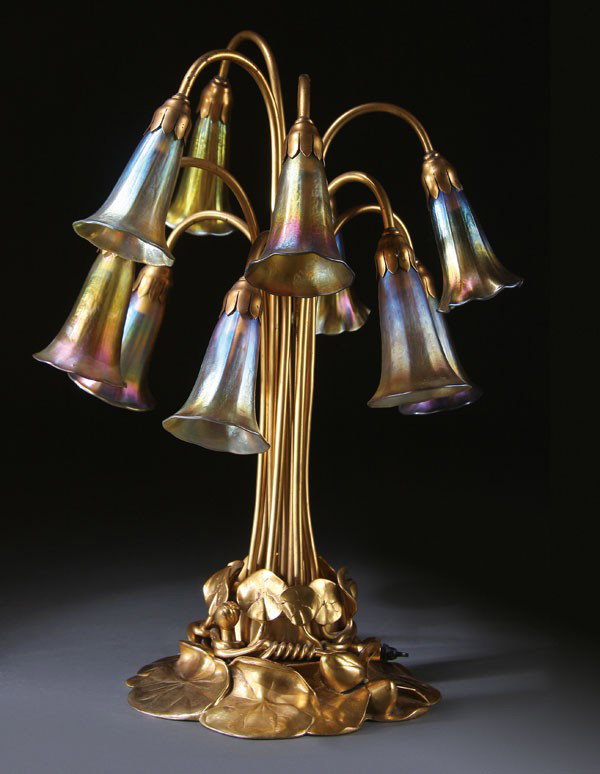 TIFFANY STUDIOS GILT BRONZE & FAVRILE LILY LAMP: A FINE TIFFANY STUDIOS GILT BRONZE AND FAVRILE GLASS TEN LIGHT LILY LAMP, EARLY 20TH CENTURY. The floriform stems with iridized gold Favrille glass lily form shades rising from a lily leaf sculpted gi
