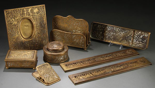 TIFFANY STUDIOS BRONZE & FAVRILE GLASS DESK SET: A TIFFANY STUDIOS GILT BRONZE AND FAVRILE GLASS "PINE NEEDLE" EIGHT PIECE DESK SET, EARLY 20TH CENTURY. Comprising a 6.25 inch x 6.75 inch oval picture frame #949, a double letter stand # 1019, a pen 
