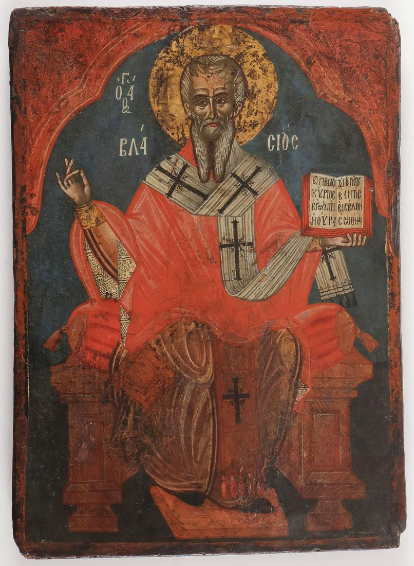A GREEK ICON OF ST. BLAISE, 18TH C: A GREEK ICON OF ST. BLAISE, 18TH C. Comprising an icon of the Bishop Saint Blaise, executed within an arched reserve and seated on a throne. He delivers a blessing with right hand and holds an open bo