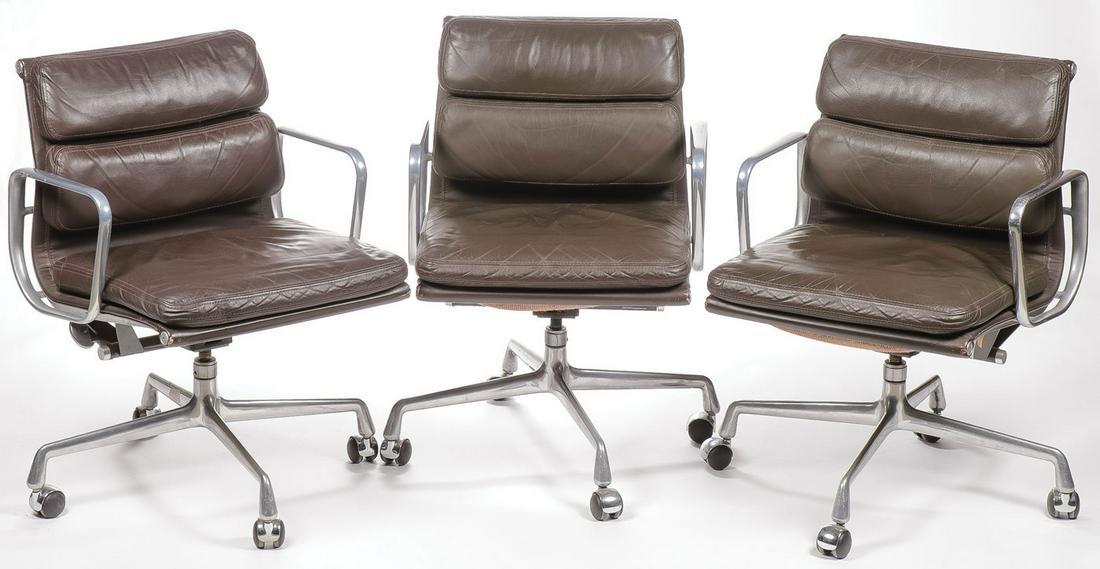 CHARLES EAMES/HERMAN MILLER SOFT PAD ARM CHAIRS: CHARLES EAMES/HERMAN MILLER SOFT PAD ARM CHAIRS. Comprising three circa 1990 low back soft pad rolling office chair by Charles Eames for Herman Miller, upholstered in brown leather, each with original