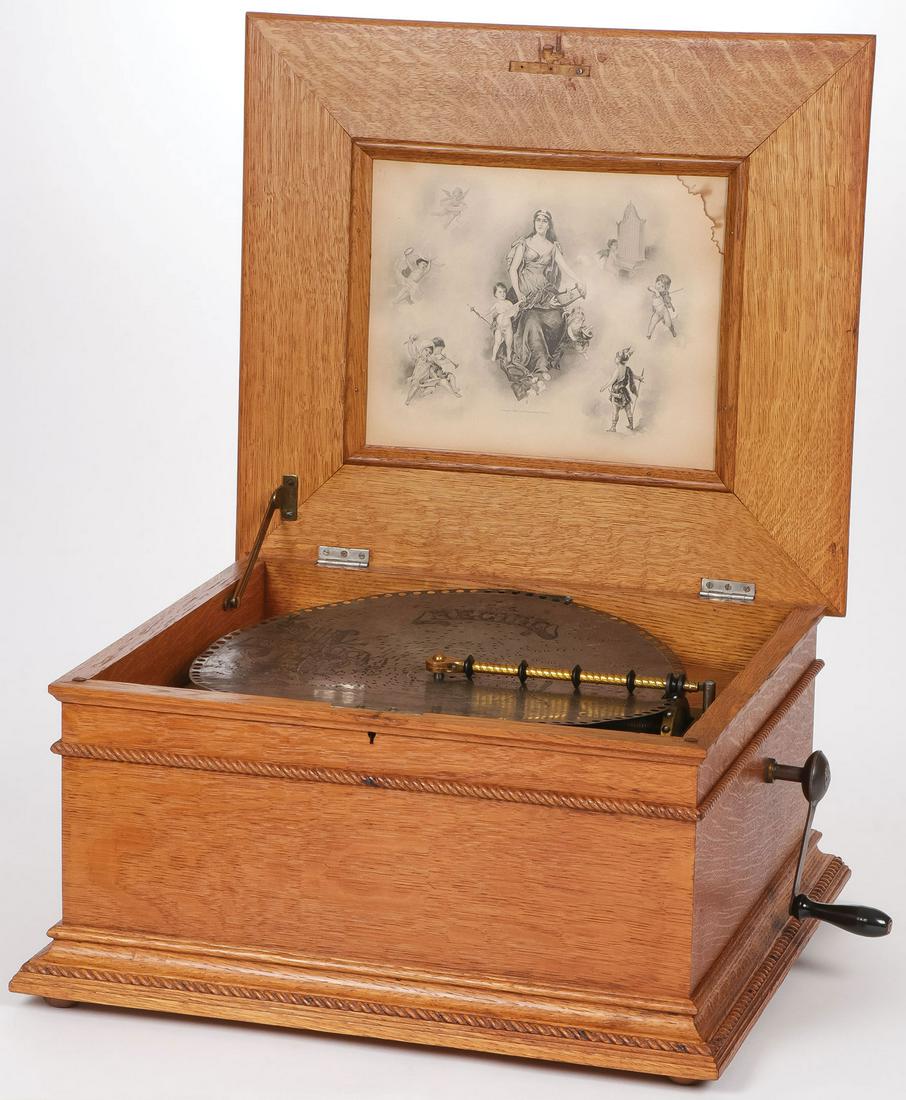 A REGINA DISC MUSIC BOX: A REGINA DISC MUSIC BOX. Oak case, interior of hinged lid with original lithograph print, last patent date May 1897, with original crank handle, takes a wind and runs, and includes eleven 15.5-inch di
