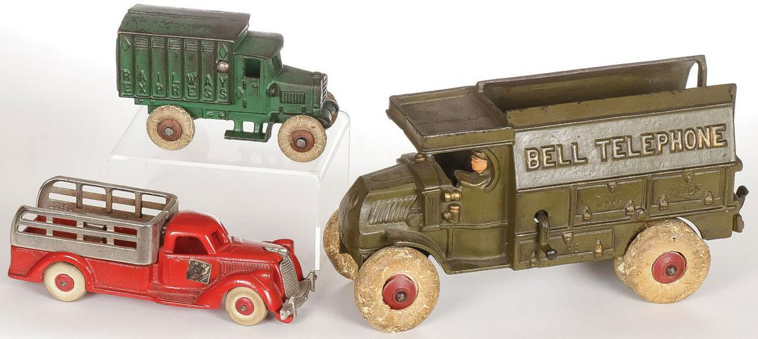 THREE CAST IRON HUBLEY TRUCKS: THREE CAST IRON HUBLEY TRUCKS. Comprising a Bell Telephone truck, a Railway Express truck, and a farm truck with nickled grill and rails. Each with rubber tires and in original paint. Greatest length 