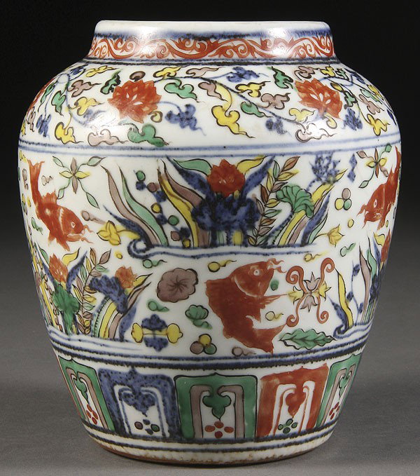 A CHINESE WUCAI DECORATED PORCELAIN JAR: A GOOD CHINESE WUCAI DECORATED PORCELAIN JAR, POSSIBLY LATE MING DYNASTY. Of ovoid shouldered form with underglaze blue foliates enameled with yellow-green and red oxide fish forms. Height 5.5 inches 