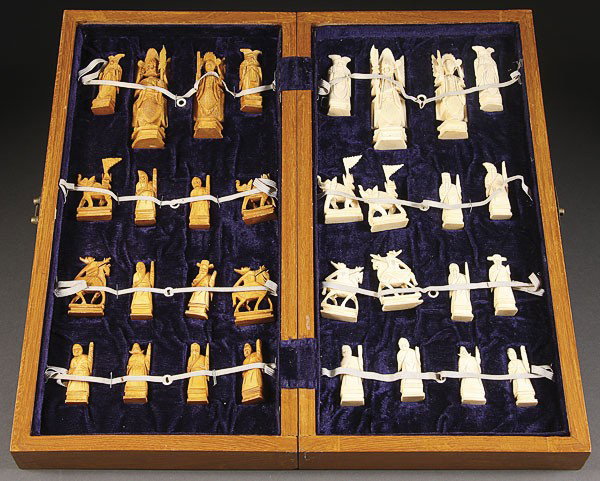 A CHINESE EXPORT CARVED IVORY CHESS SET: A CHINESE EXPORT CARVED IVORY CHESS SET, 20TH CENTURY. A complete set modeled as warriors in natural and tea stained ivory contained in a fitted hardwood-checkerboard case. The figures 2.25-4 inches,