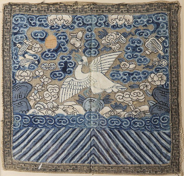 A PAIR OF CHINESE CHING DYNASTY EMBROIDERED PANEL: A PAIR OF CHINESE CHING DYNASTY EMBROIDERED PANELS, each of matching design depicting a phoenix in flight among clouds and scattered Buddhist symbols. 12 inches square (30 cm), contained in a glazed a