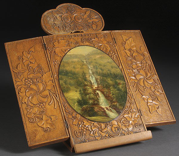 A SWISS CARVED-BLACK FOREST WOOD TRIPTYCH FRAME: A SWISS CARVED-BLACK FOREST WOOD TRIPTYCH FRAME exhibiting an oval handpainted scene of the waterfalls at Geisbach, Switzerland, 19th century. Overall carved in high relief of scrolling foliage and fl