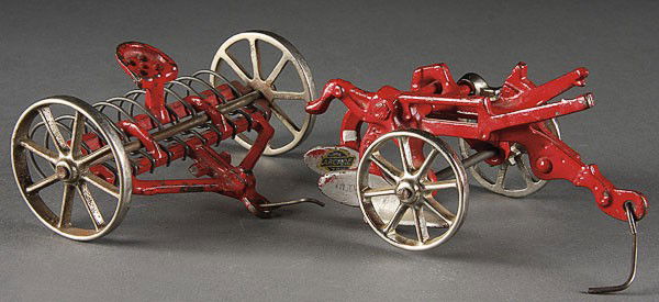 A GROUP OF TWO ARCADE CAST IRON TOY FARM IMPLEMENT: A GROUP OF TWO ARCADE CAST IRON TOY FARM IMPLEMENTS, EARLY 20TH CENTURY, comprising a two bottom plow and hay rake. Length 5.5 inches.
