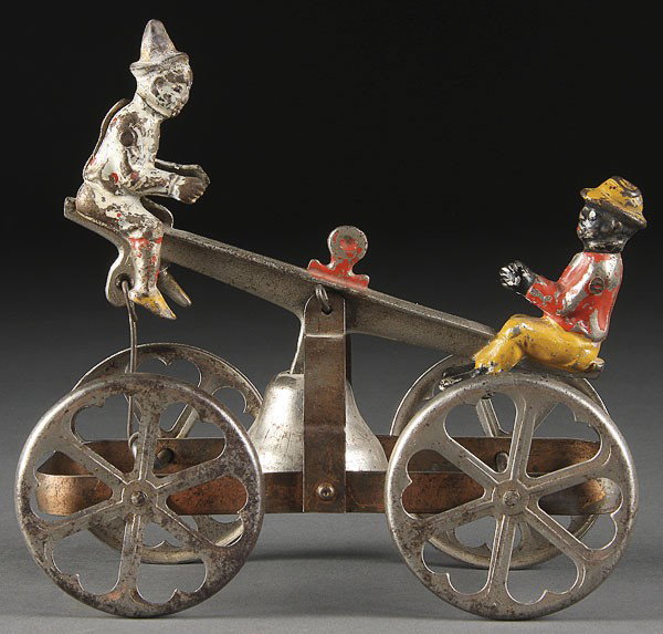 A FINE WALTROUS TOY SEA-SAW BELL RINGER: A FINE WALTROUS TOY SEASAW BELL RINGER, LATE 19TH CENTURY, cast iron and pressed steel, depicting a black man and clown figure. Length 6.5 inches.