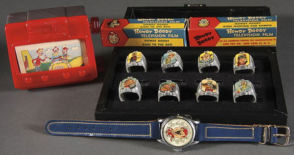 HOWDY DOODY WRIST WATCH NOVELTY TELEVISION: A HOWDY DOODY WRIST WATCH, NOVELTY TELEVISION AND VARI-VUE FINGER RING COLLECTION, MID 20TH CENTURY, comprising a Swiss watch with blue band, eight different plastic rings with characters, and a plast