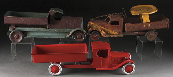 THREE PRESSED STEEL TOY TRUCKS, CIRCA 1930S: THREE PRESSED STEEL TOY TRUCKS, CIRCA 1930'S, comprising a Buddy L sit and ride, a Structo dump truck, and a reproduction steel dump truck. Length 24 inches.