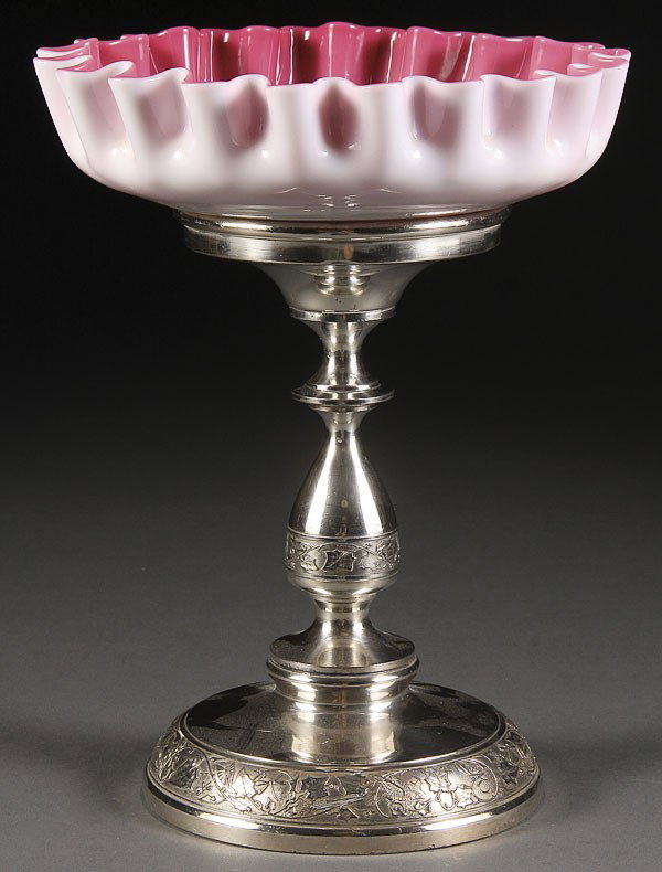 VICTORIAN CASED GLASS SILVER PLATE CENTERPIECE: A VICTORIAN CASED GLASS AND SILVER PLATE CENTER PIECE, LATE 19TH CENTURY. Comprising a pink cased ruffled bowl rising from a Middletown plate pedestal with embossed designs. Height 10.25 inches.