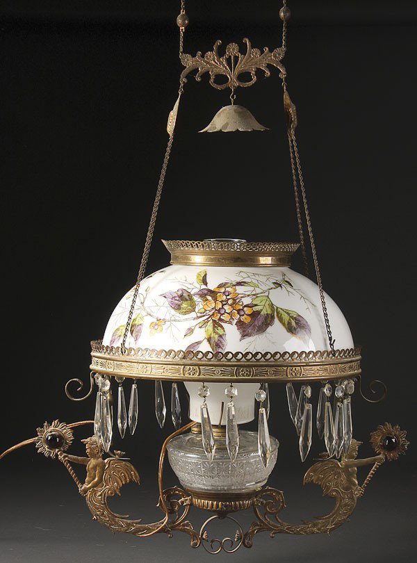A VICTORIAN JEWELED FRAME PARLOR LAMP, CIRCA 1900: A VICTORIAN JEWELED FRAME PARLOR LAMP, CIRCA 1900. The electrified pull down frame with wind angels supporting jeweled mounds below a transfer decorated opal shade with cut prism pendants. Diameter 14