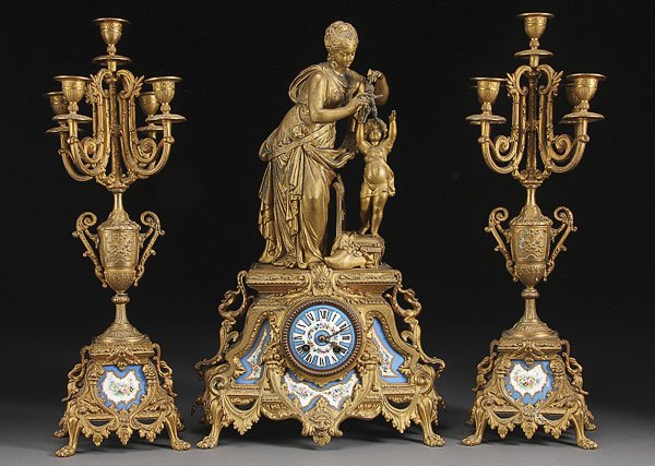 NAPOLEON III SEVRES STYLE CLOCK GARNITURE, 19TH C: A FRENCH NAPOLEON III SEVRES STYLE PORCELAIN AND ORMOLU CLOCK GARNITURE, LATE 19TH CENTURY. Neatly embossed clock case containing three hand painted porcelain tiles and porcelain clock face surmounted