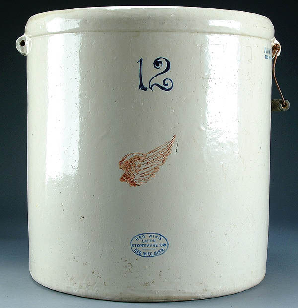 A REDWING 12 GALLON CROCK with lid. Small wing an: A REDWING 12 GALLON CROCK with lid. Small wing and blue oval marked "Union Stoneware Co." Missing one handle, some losses. Does not include lid. Height 19". Estimate $75-$150