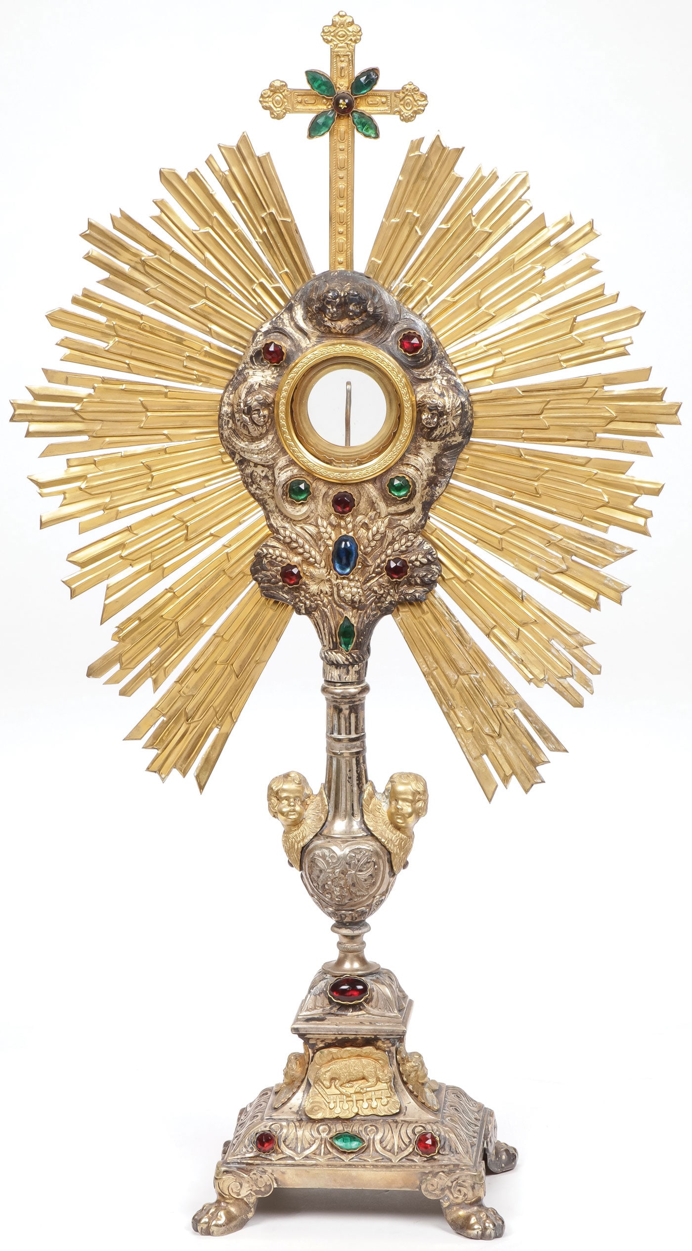 ORNATE SILVER GILT MONSTRANCE 19TH C: ORNATE SILVER GILT MONSTRANCE 19TH C. Resting on four paw feet the base with winged cherub heads, the Angus Dei and cabochons beneath a heart shaped node mounted with winged cherub heads supporting a