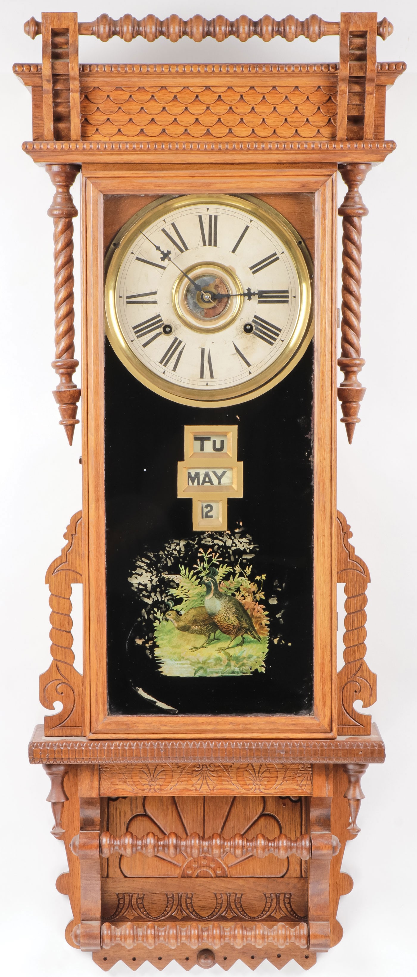 GILBERT CALANDER OAK WALL REGULATOR: GILBERT CALANDER OAK WALL REGULATOR Comprising a Gilbert, oak calendar wall regulator, fancy carved oak case, 8-day calendar, day, month, date, original glass with quail, good complete paper label on 