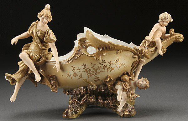 JAPANESE PORCELAIN CENTERPIECE COUPE: A JAPANESE FIGURAL PORCELAIN CENTERPIECE COUPE IN THE VICTORIAN STYLE, 20TH CENTURY. Depicting a young beauty with putti. Crossed arrow marks on base. Length 15.5 inches (39 cm).