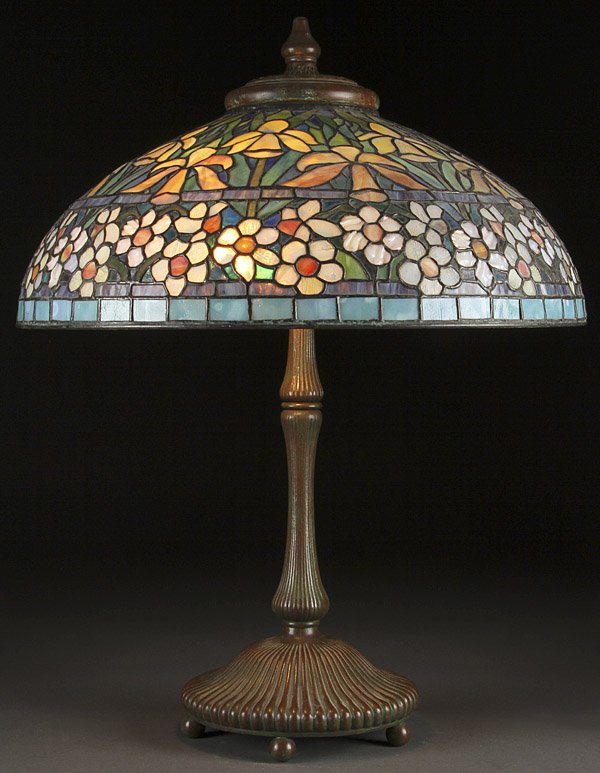 REPRODUCTION TIFFANY TABLE LAMP: A VERY FINE CENTURY STUDIOS LEADED GLASS AND BRONZE REPRODUCTION TIFFANY TABLE LAMP, LAST QUARTER 20TH CENTURY. With Irish and white blossom border on a verdi gras patina bronze base. Inscribed "#9303