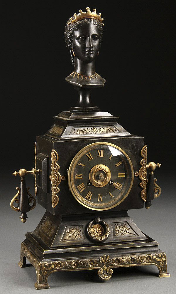 A FRENCH AESTHETIC MOVEMENT TABLE CLOCK: A FRENCH AESTHETIC MOVEMENT TABLE CLOCK, LATE 19TH CENTURY. The case with dark brown patina decorated with intaglio foliates below a figural sculpted bust. Height 18 inches (46 cm).