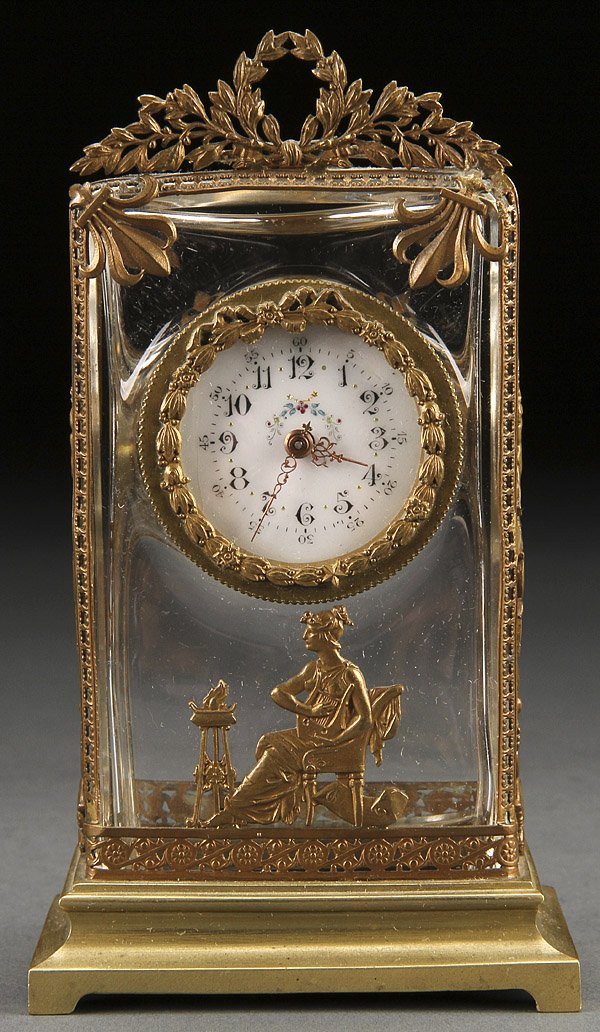 GILT BRONZE MOUNTED CRYSTAL DESK CLOCK: A FINE NEOCLASSIC GILT BRONZE MOUNTED CRYSTAL DESK CLOCK, PROBABLY FRENCH. Depicting classical figures and scrolled foliates below an enamel decorated dial. Height 6.25 inches (16 cm).