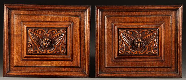 SWISS CARVED BLACK FOREST OAK PANELS: A FINE PAIR OF SWISS CARVED BLACK FOREST WINGED CHERUBS HEAD OAK PANELS, CIRCA 1900. With an extending facial mask set within stepped molded borders, later mounted as wall plaques, 12.75 inches x 15 i