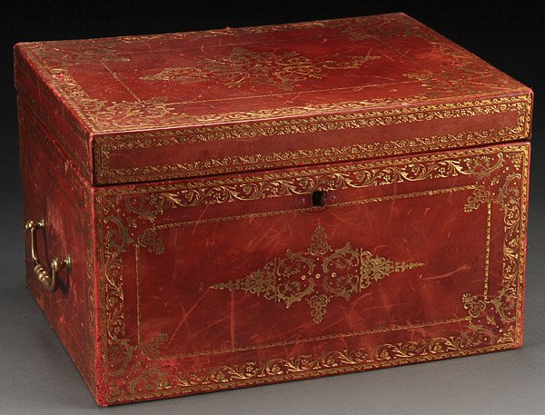ENGLISH EMBOSSED & GILT LEATHER COVERED CASKET: A FINE ENGLISH EMBOSSED AND GILT LEATHER COVERED CASKET, CIRCA 1900. Covered overall in red leather with embossed and gilt scrolled decoration, the end panels with gilt bronze bale handles. Length 14.