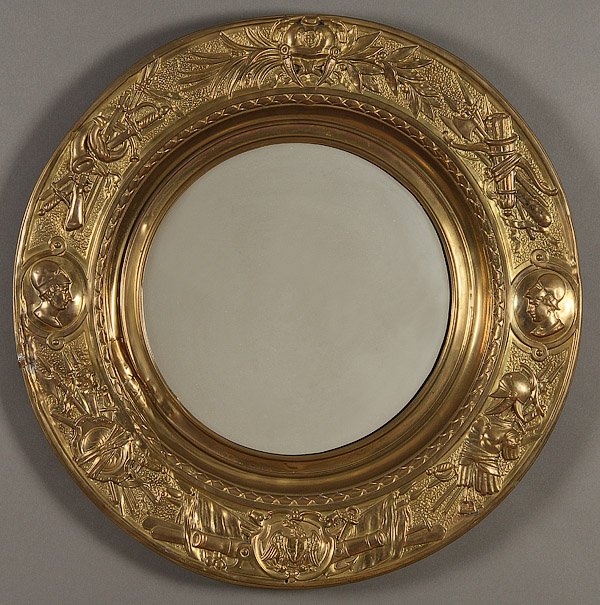 A NEOCLASSIC BRASS REPOUSSE FRAMED WALL MIRROR: A NEOCLASSIC BRASS REPOUSSE ROUND FRAMED WALL MIRROR, LATE 19TH CENTURY. Embossed with various arms, armor and portrait busts. Diameter 27 inches (68.6 cm).