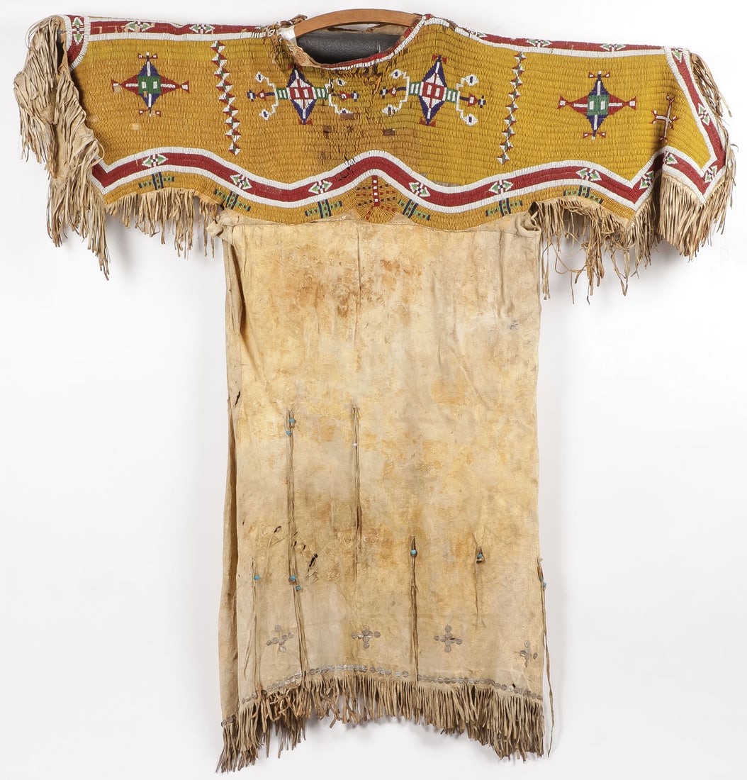 SIOUX BEADED HIDE DRESS, C. 1880: SIOUX BEADED HIDE DRESS, C. 1880. Comprising a good legitimate sinew-sewn hide dress with impressive fully beaded yoke in geometrical patterns, lazy-stitched on a predominately greasy yellow field wit