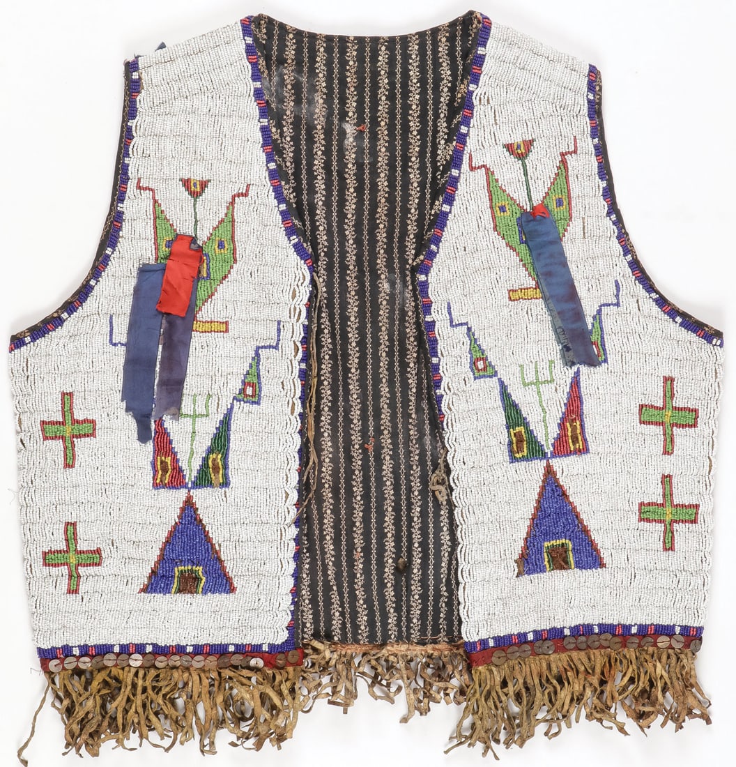A GOOD SIOUX BEADED VEST, CIRCA 1890: A GOOD SIOUX BEADED VEST, CIRCA 1890. Finely beaded overall with geometric patterns, crosses, and silk ribbon drops. Sinew and lazy stitched on hide base, the waist banded with, fringe, and sequins. T