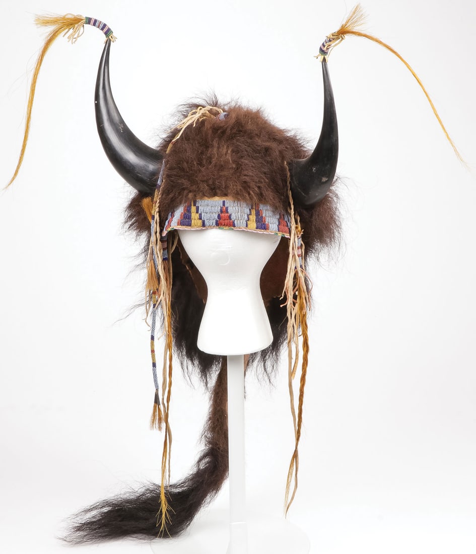 PLAINS STYLE BUFFALO SPLIT-HORN BONNET: PLAINS STYLE BUFFALO SPLIT-HORN BONNET. Of traditional design, possibly Cheyenne. Sinew-sewn hide and lazy-stitched beaded headband, with beaded and braided dyed horsehair drops. The horn tips termina