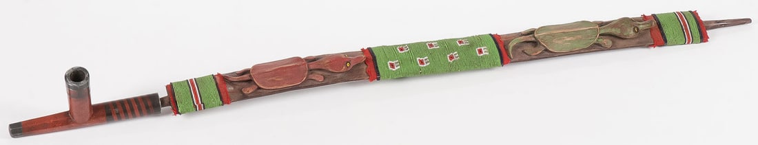 A PLAINS PIPE AND STEM: A PLAINS PIPE AND STEM. The catlinite bowl of typical design with inlaid pewter banding, length 6.75 inches, and a carved stem with turtle effigies, red trade wool, and beaded banding, as shown. Overa