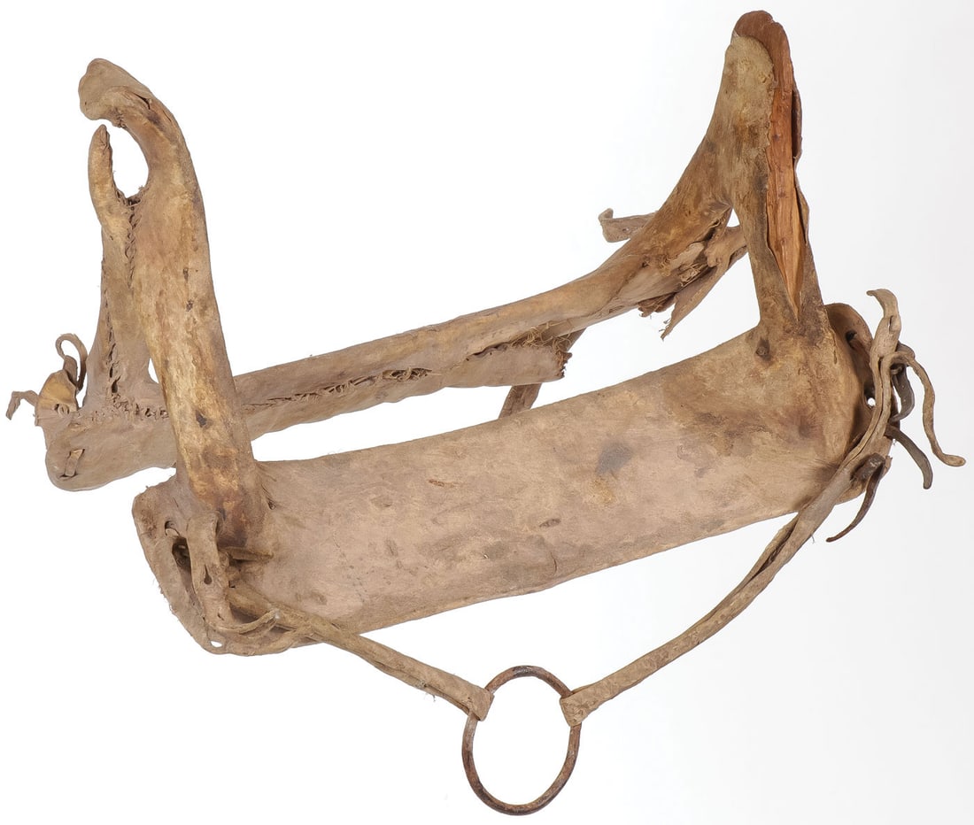 A PLAINS HIDE WRAPPED WOMAN'S SADDLE: A PLAINS HIDE WRAPPED WOMAN'S SADDLE. Of traditional form, the wood A-frame wrapped in hide and sinew-sewn. Length 20 inches, height 12 inches. SHIPPING NOTICE: Except for large, oversized items, Jack