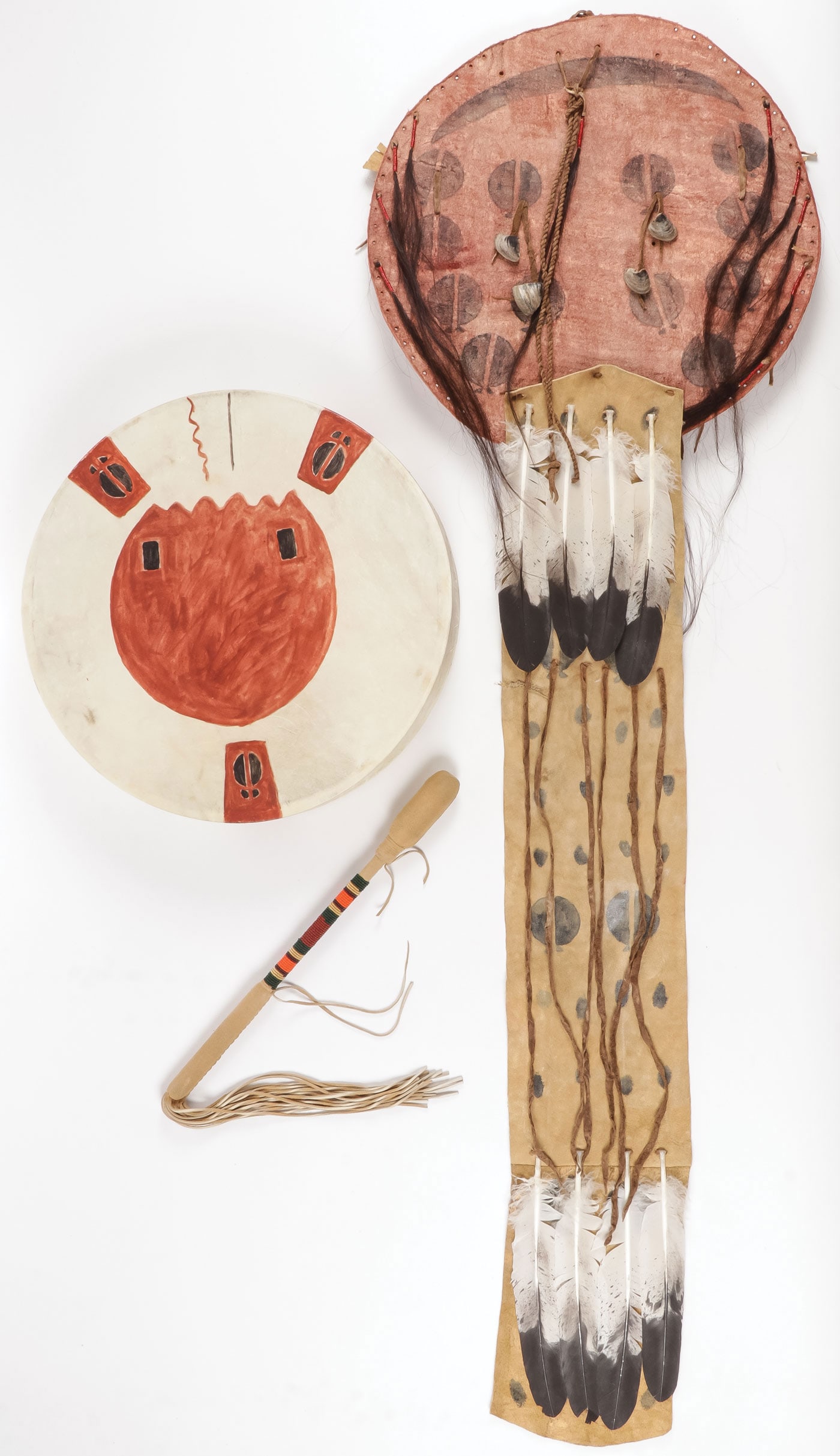 PLAINS STYLE DRUM AND SHIELD: PLAINS STYLE DRUM AND SHIELD. Comprising a polychrome stretched hide drum with beaded stick and a Plains style hide shield with horsehair quilled drops and painted goose feather decoration. Contempora