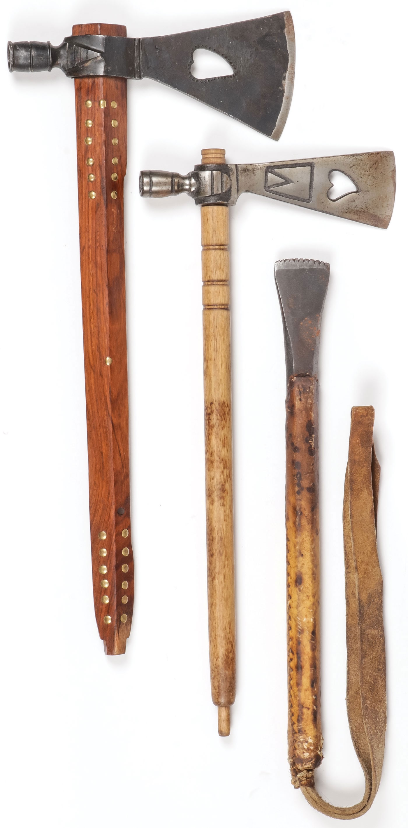 A PAIR OF TRADE AXE PIPES: A PAIR OF TRADE AXE PIPES. Both blades with heart-shaped cutouts, and one stem with brass tacks. Together with a sinew-sewn hide wrapped chisel with strap handle. Greatest measurement is 18.75 inches.