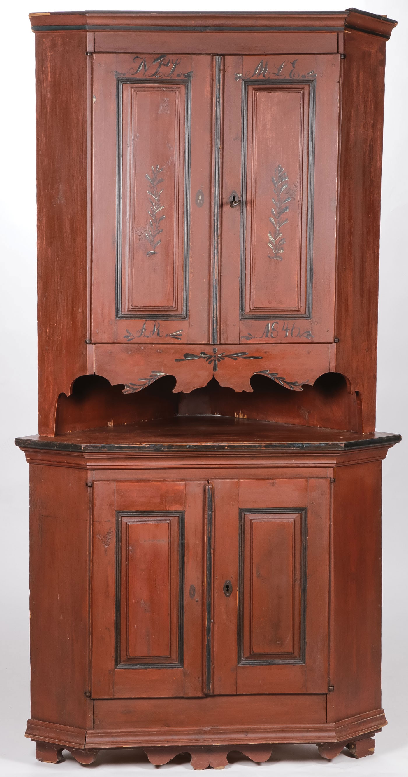 GREAT NORWEGIAN PAINTED CORNER CABINET: GREAT NORWEGIAN PAINTED CORNER CABINET. Of traditional form. Wood peg construction, scalloped feet, paneled doors, and the interior with built-in spoon rack above shelves. Overall in red and black pai