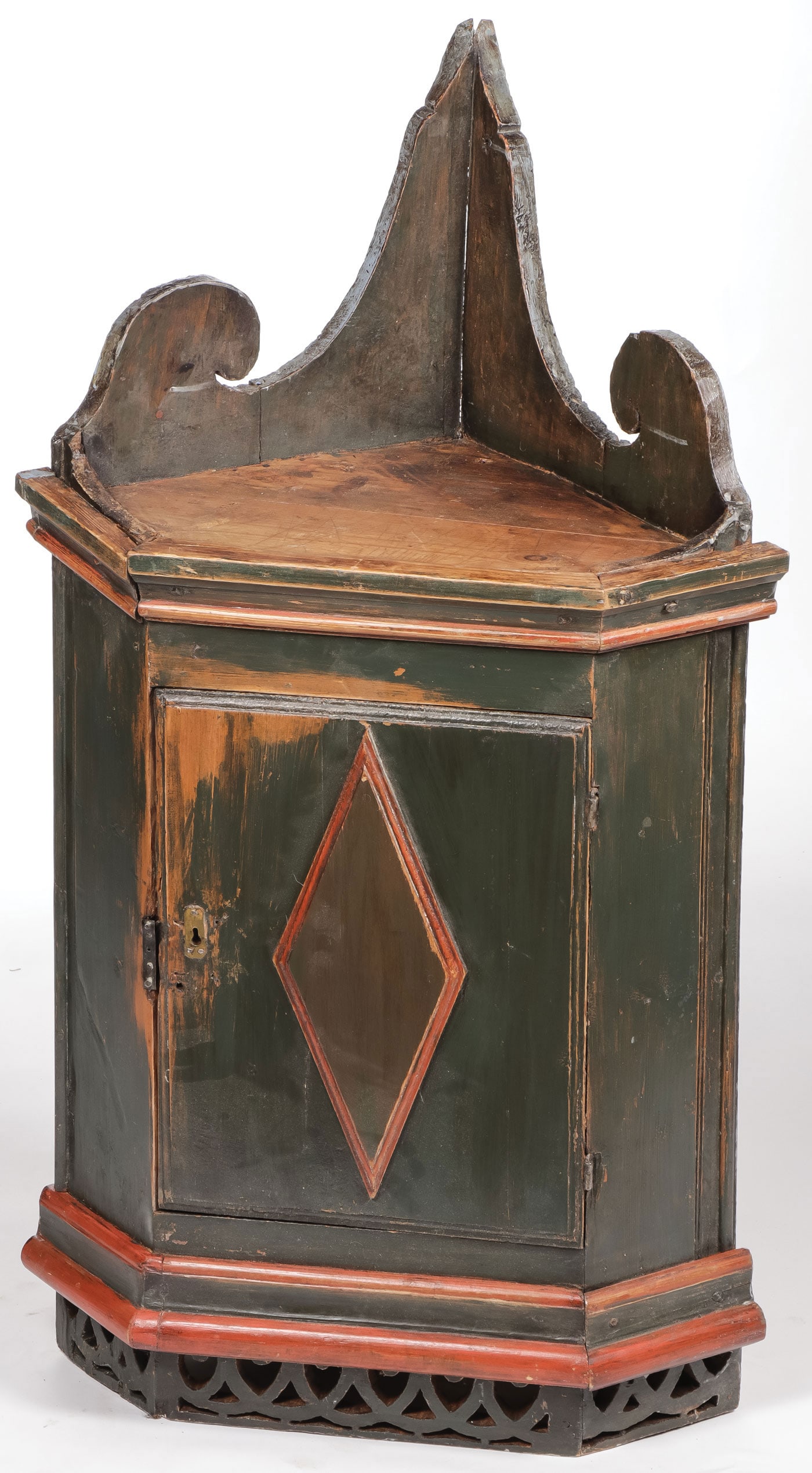 NORWEGIAN CORNER HANGING CABINET: NORWEGIAN CORNER HANGING CABINET. With pierced skirt, raised diamond door plaque, overhanging molded crown and shaped finial. In original paint with honest ware and patina. Height 49 inches, width 27.