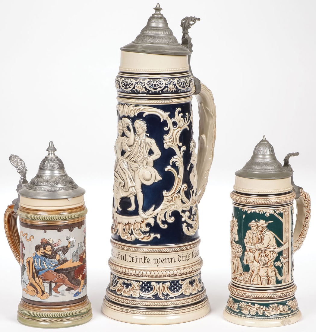 GROUP OF THREE GERMAN BEER STEINS: GROUP OF THREE GERMAN BEER STEINS. The largest model #1693 by Marzi & Remy depicting dancing couple with cherubs amongst foliage, height (including pewter lid) 17.25 inches (44 cm). Together with a Th