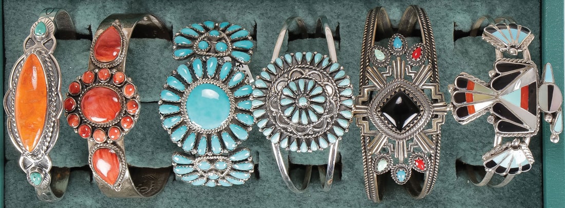 SIX SOUTHWEST STYLE SILVER CUFF BRACELETS: SIX SOUTHWEST STYLE SILVER CUFF BRACELETS. Pictured left to right, the first example with orange center stone encircled by faux applied silver rope border flanked by two small turquoise cabochons, int