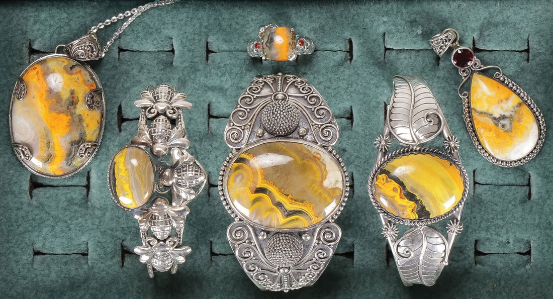 ATTRACTIVE BUMBLEBEE JASPER JEWELRY GROUP: ATTRACTIVE BUMBLEBEE JASPER JEWELRY GROUP. Comprising a large oval pendant suspended from dainty silver chain, three cuff bracelets, a ring with square cut center stone flanked by red accent gemstones