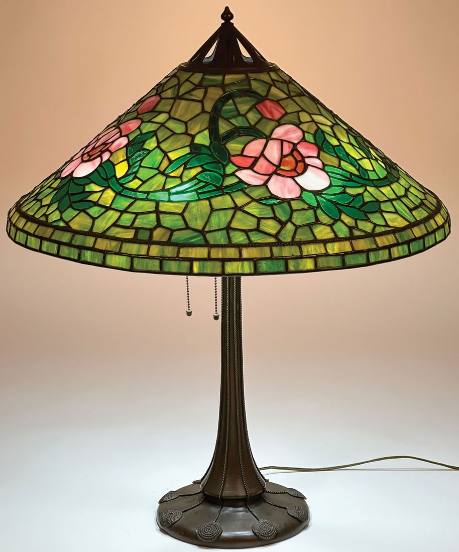 LARGE BRONZE HANDEL LEADED GLASS TABLE LAMP: LARGE BRONZE HANDEL LEADED GLASS TABLE LAMP. Comprising a conical leaded glass shade decorated with swirling peonies or magnolias. The interior shade with soldered metal HANDEL label, possibly added l