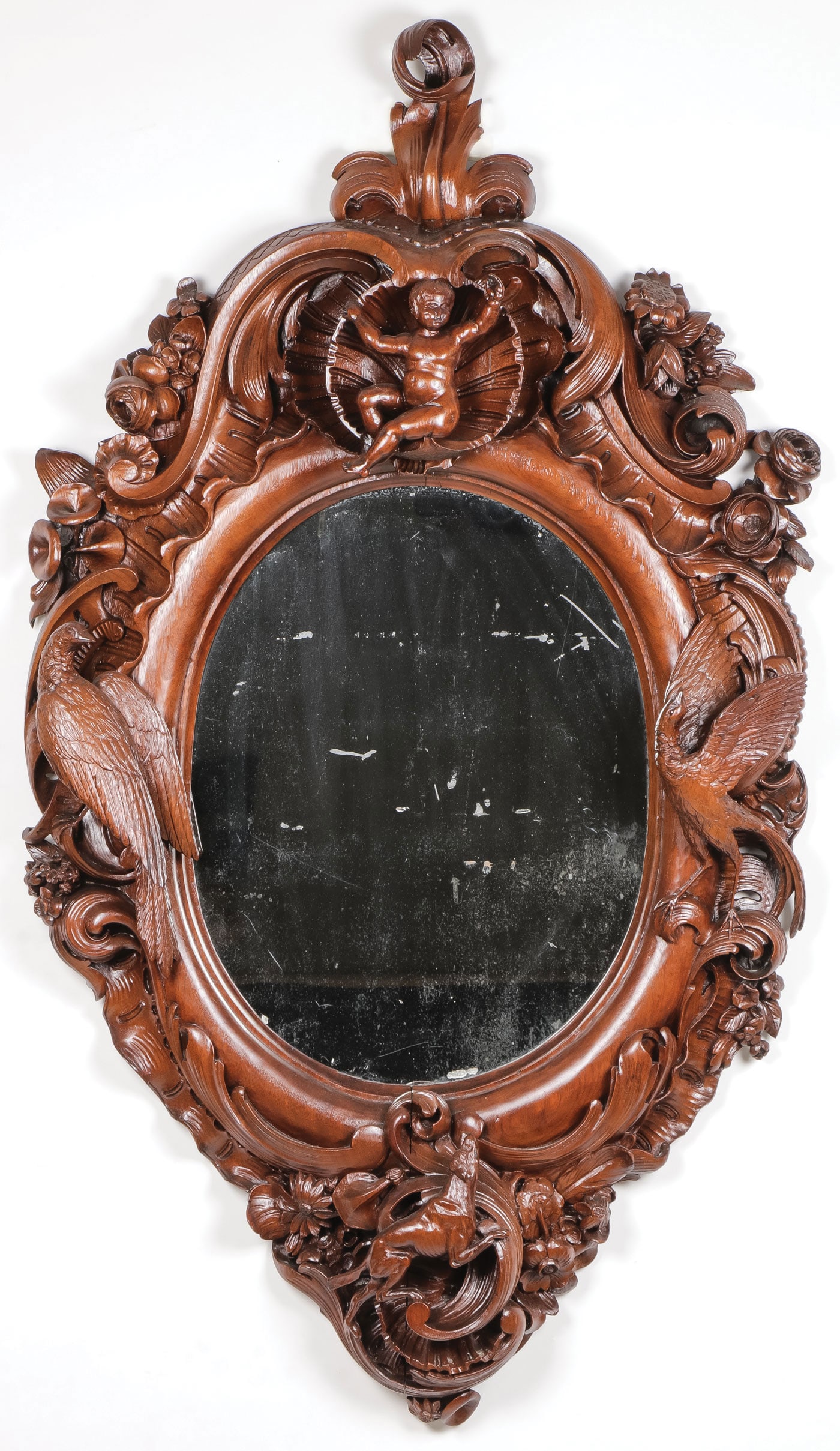 ROCOCO STYLE CARVED WALNUT MIRROR, 19TH C: ROCOCO STYLE CARVED WALNUT MIRROR, 19TH C. The frame carved with Rocaille scrolls, set with flowerheads, atop a putti within a clam shell, on each side game birds, and below a pursuing hunting dog enc