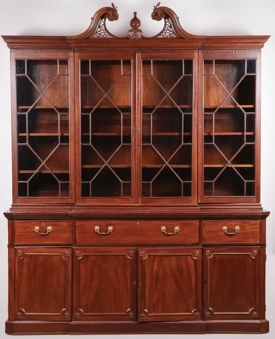 A GEORGIAN MAHOGANY BREAKFRONT SECRETARY, 18TH C: A GEORGIAN MAHOGANY BREAKFRONT SECRETARY, 18TH C. Of traditional form, the broken arch pediment centered with an urn finial over four glazed doors, above a center secretary fold out drawer with felt c