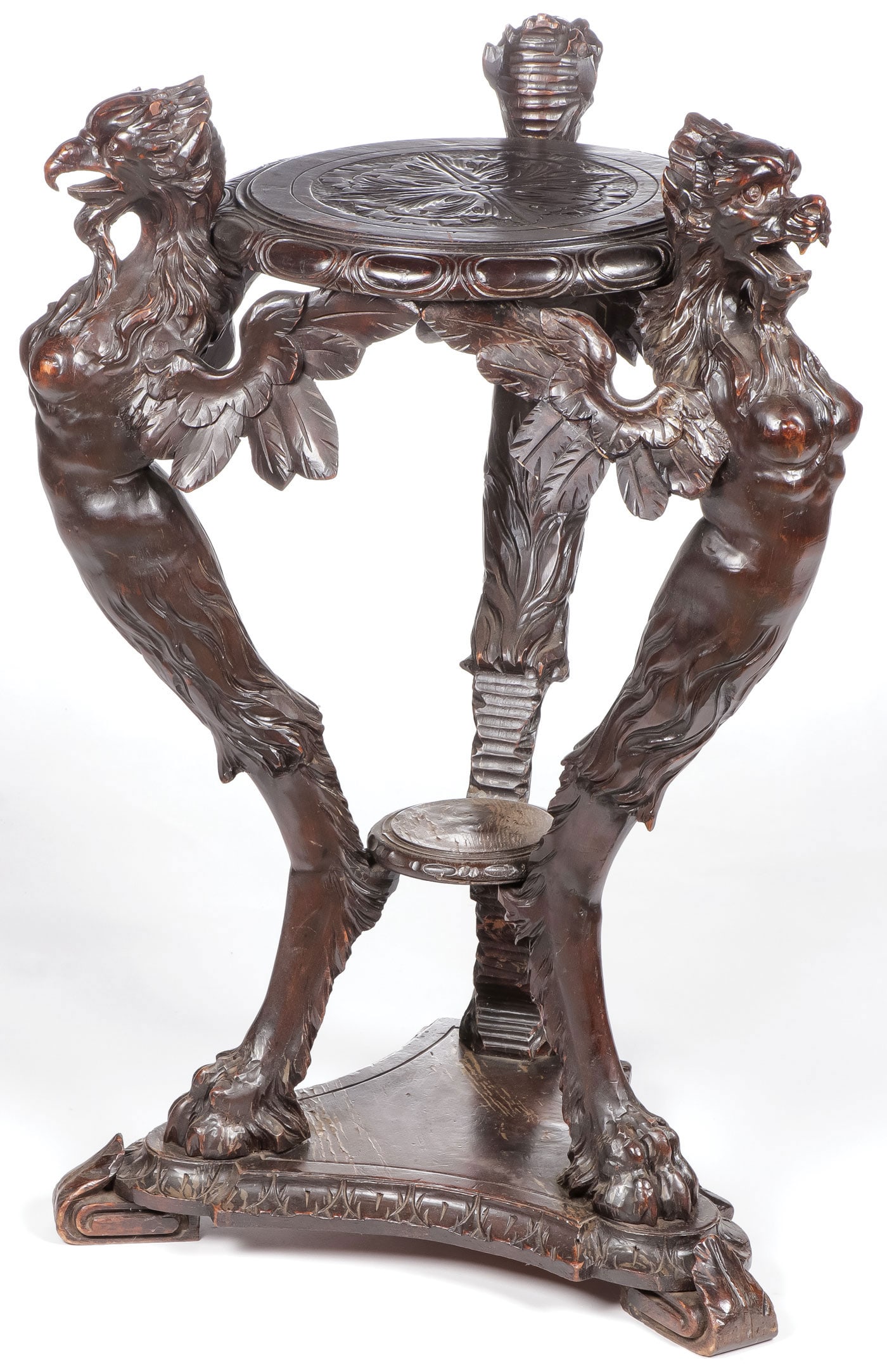 HEAVILY CARVED PEDESTAL STAND, C. 1875: HEAVILY CARVED PEDESTAL STAND, C. 1875. Comprising an impressive Renaissance revival carved pedestal stand. The supports modeled as breasted winged griffins supporting a relief carved circular platfor